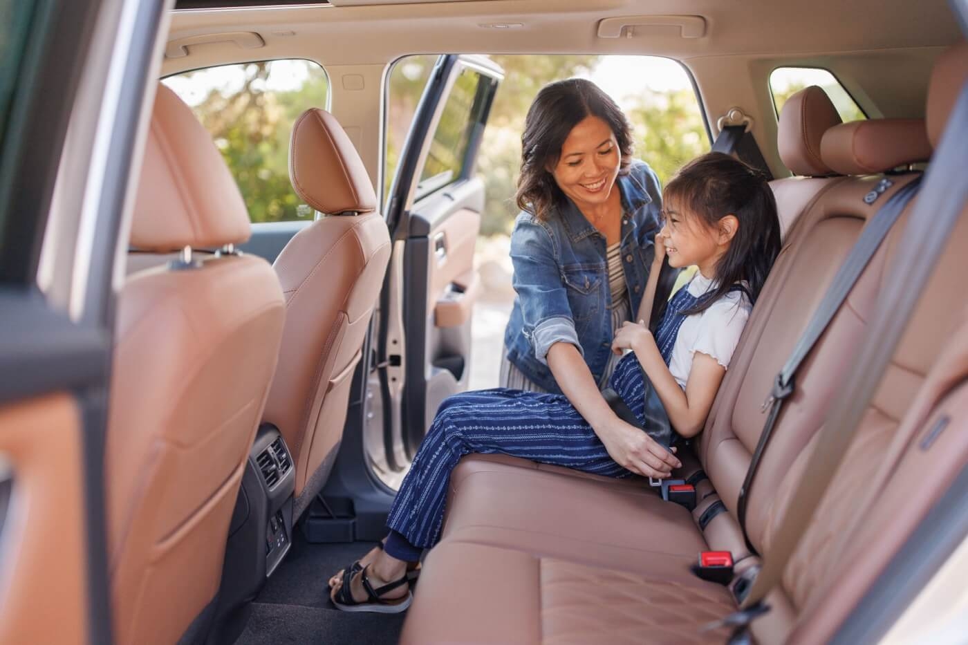 Mère attachant la ceinture de sécurité à sa fille à bord du Nissan Rogue 2026.