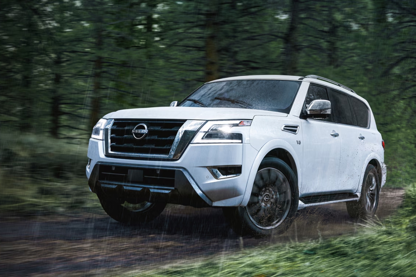  Vue 3/4 avant et latérale du Nissan Armada intérieur sur sentier de forêt un jour de pluie